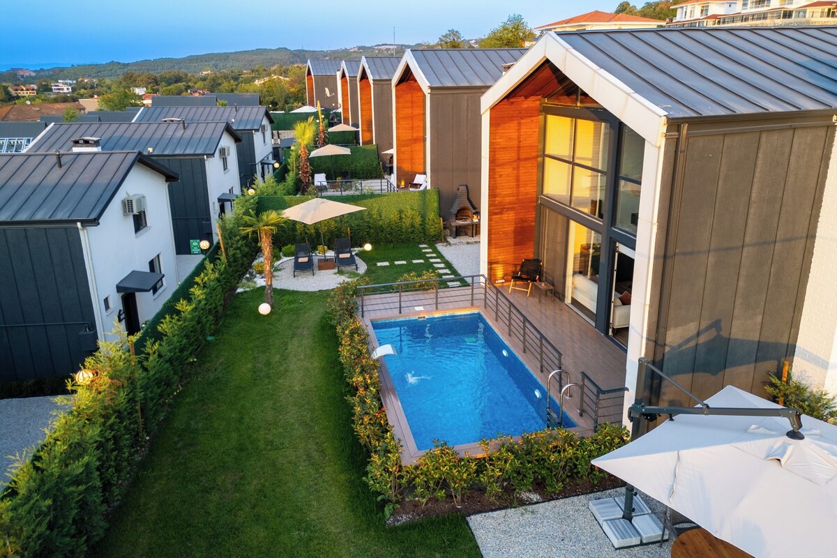 A modern residential area with a swimming pool, wooden houses, and a well-maintained lawn.