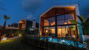 A modern house with a large glass facade, a swimming pool, and a well-lit interior. - Trio Palazio Sapanca (Sapanca)