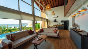 A spacious living area with a large window overlooking a pool and mountains, a cozy seating area, and a modern kitchen. - Trio Palazio Sapanca (Sapanca)