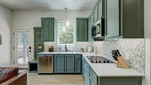 A kitchen with green cabinets, a white countertop, and a built-in dishwasher. - New Guesthouse w/ Private Patio, Fast WiFi, 1 bed/1 bath (Edmond)