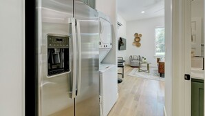 A modern kitchen with a stainless steel refrigerator, a built-in water dispenser, and a compact washer-dryer unit. - New Guesthouse w/ Private Patio, Fast WiFi, 1 bed/1 bath (Edmond)