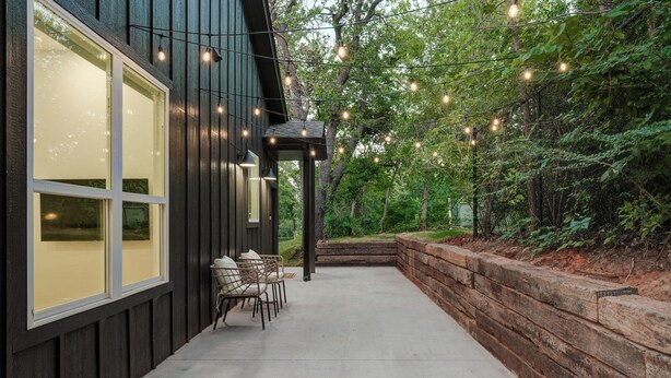 A building with large windows, a patio with chairs, and string lights. - New Guesthouse w/ Private Patio, Fast WiFi, 1 bed/1 bath (Edmond)