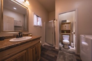 Een badkamer met een wastafel, spiegel, douche, toilet en opbergkasten.