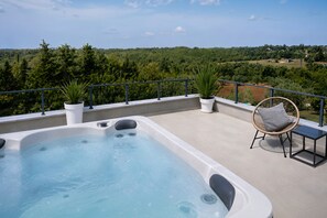 A hot tub on a balcony with a view of a green landscape.