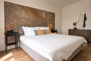 A modern bedroom with a large bed, two bedside tables, a dresser, and a wall-mounted mirror. - Modern Comfort & Natural Charm – Your Private Istrian Escape (Barban)