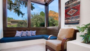 A cozy seating area with a bench and a chair, a large window with a view of a mountain, and a wall with a patterned tapestry. - Sedona Sunrise (Sedona)