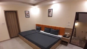 A bedroom with a large bed, a nightstand with a coffee maker, and a mirror. - Hotel Shiv Inn By T And M Hotels (Haridwar)