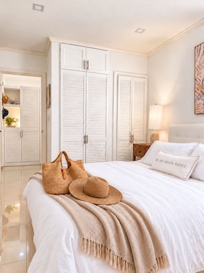 Une chambre à coucher avec un lit, une armoire blanche et un coussin sur le thème de la plage.