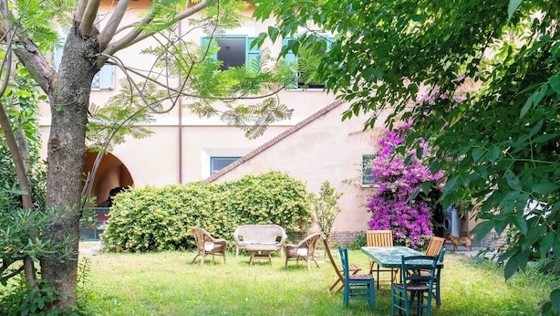 Ein Garten mit Tisch, Stühlen, einem Baum und einem Gebäude im Hintergrund.