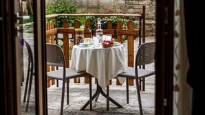 An outdoor dining area with a table set for two, surrounded by wooden chairs, against a stone wall. - Al Chiaro di Luna (Agerola)