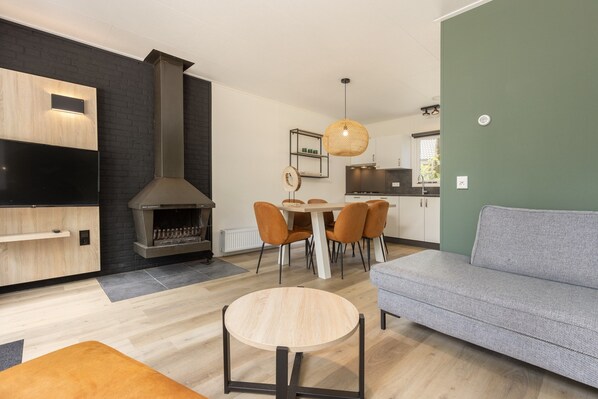 A modern living room with a fireplace, a dining area, and a sofa.