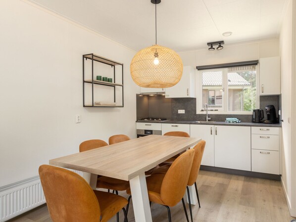 Une cuisine moderne avec des meubles blancs, une table à manger en bois et des chaises orange.