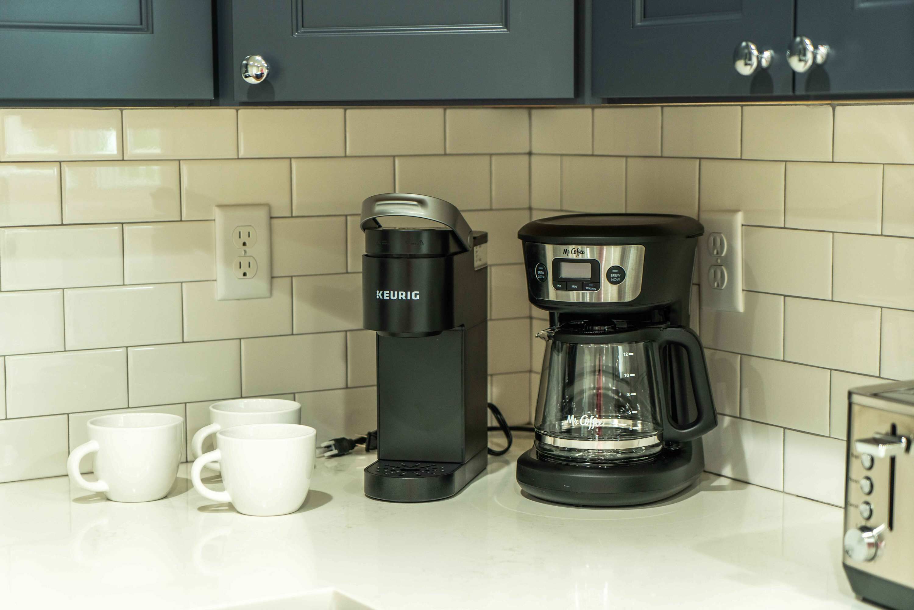 Eine Küche mit Kaffeemaschine, zwei weißen Tassen und einem Toaster.