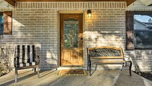 A brick house with a wooden door, a bench, and a doormat.
