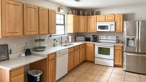 A kitchen with wooden cabinets, a white countertop, a stainless steel refrigerator, a microwave, a stove, and a dishwasher.