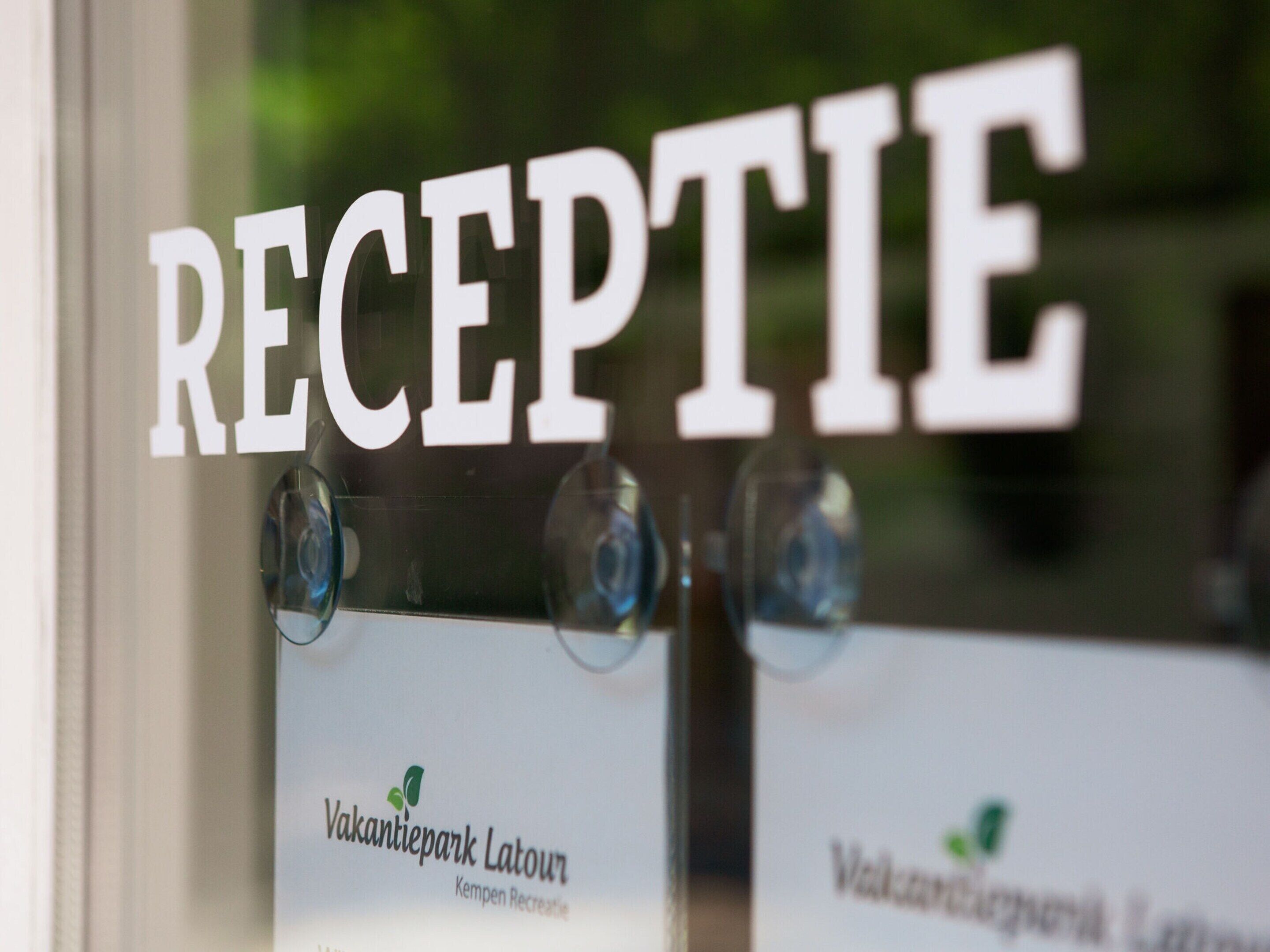 Et receptionområde med et skilt, der står 'RECEPTION', og navneskilte for 'Vakantiepark Latour' og 'Kempen Recreatie'.