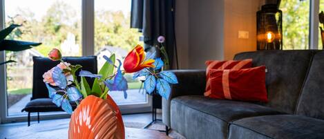 A living room with a grey sofa, a wooden coffee table, and a vase with flowers.