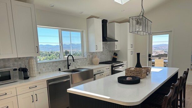 A modern kitchen with a central island, white cabinetry, and a view of the mountains. - "The Best" Jacuzzi View Private Luxury Guest Cottage-Better than a Room or Suite (Thousand Oaks)