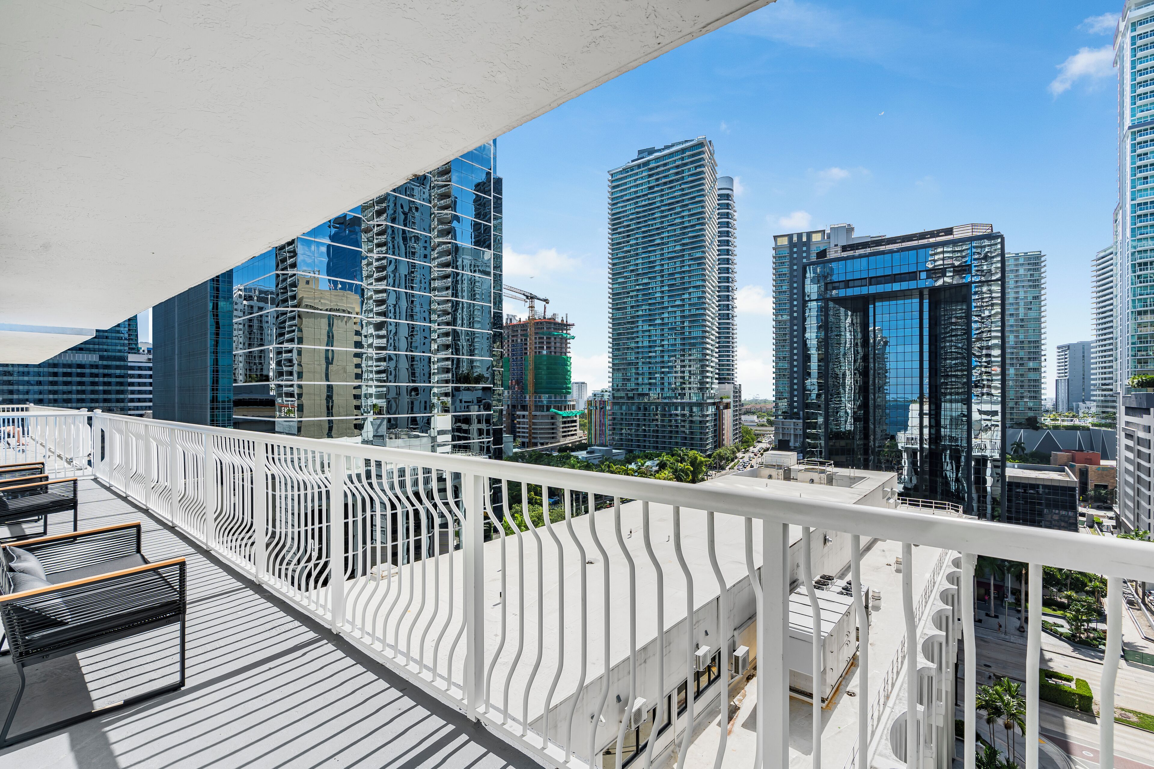 A high-rise building with a modern architectural design, featuring a balcony with white railings and seating.