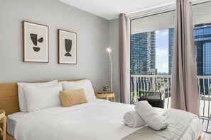 Et moderne hotelværelse med en stor seng, et natbord, en lampe og to billeder hængende på væggen.