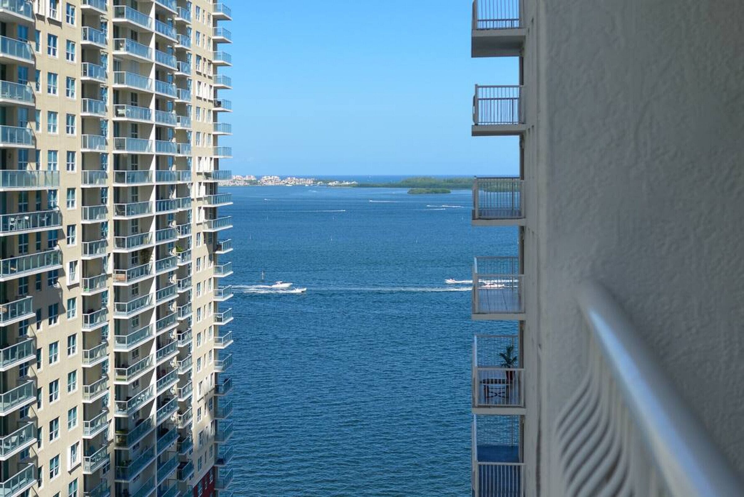 A high-rise building with multiple balconies overlooking a body of water.