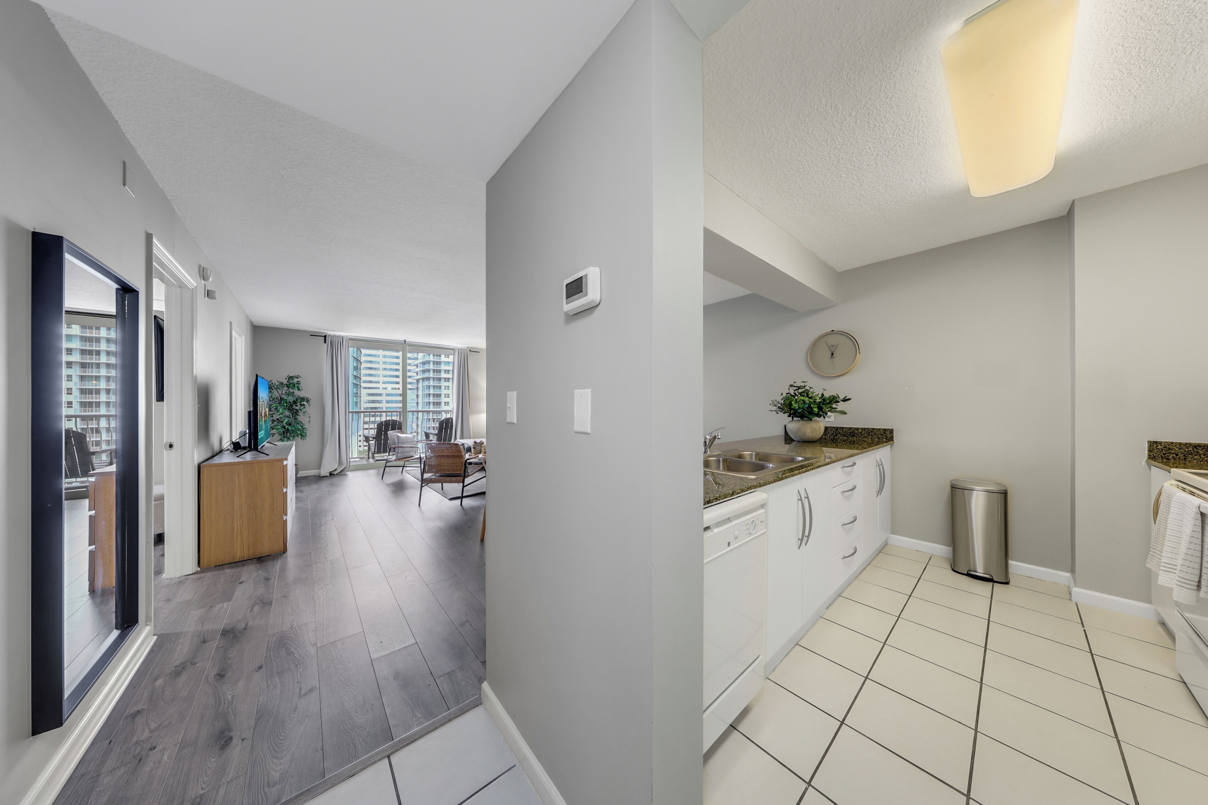 A modern kitchen with white cabinets, a stainless steel sink, and a tiled floor.