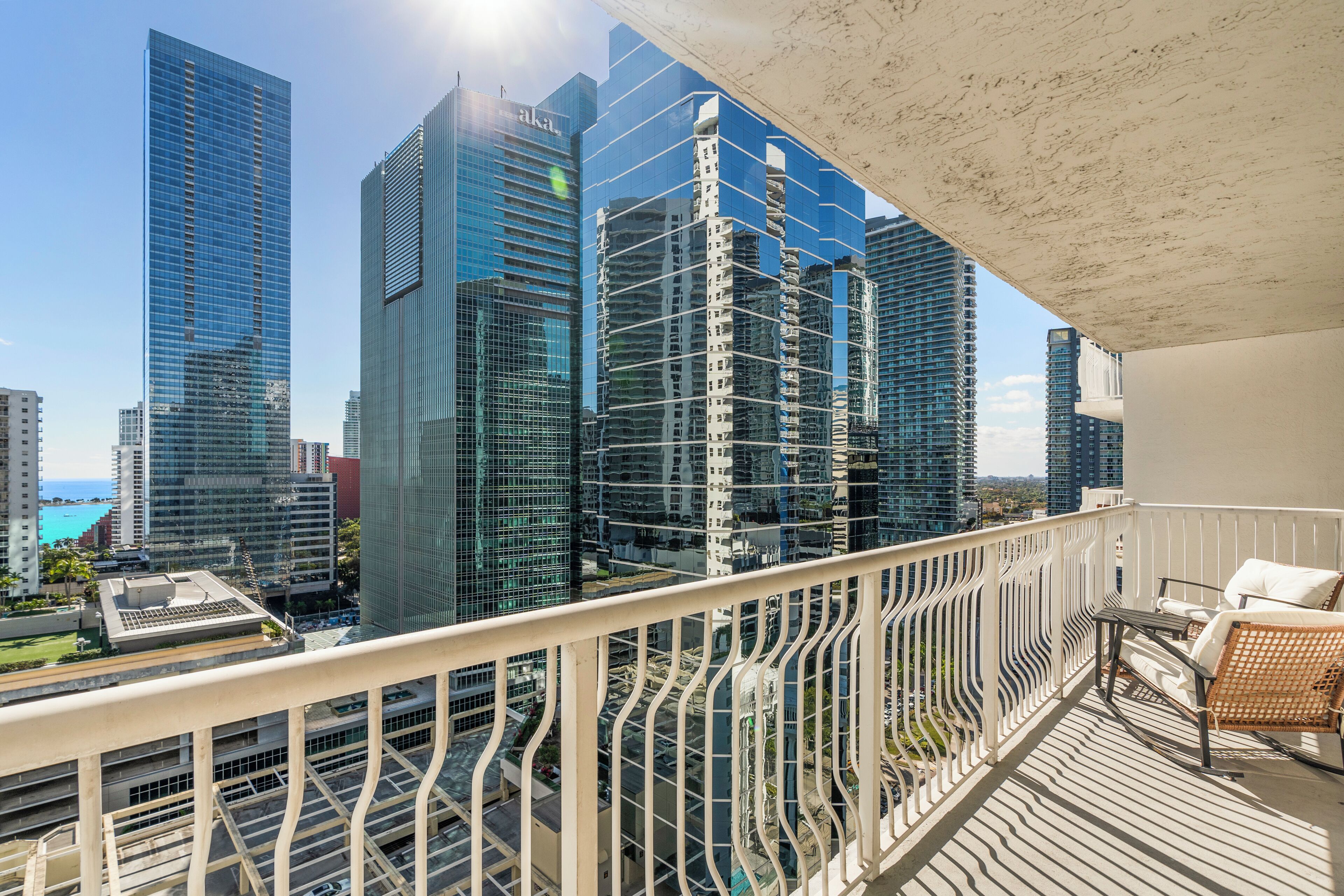 A balcony with a view of high-rise buildings, a railing, and a chair.