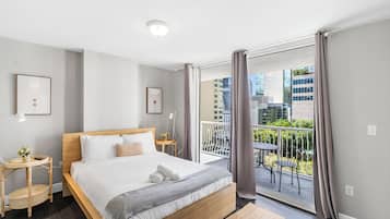 Ein modernes Hotelzimmer mit einem großen Bett, einem kleinen Beistelltisch, einem runden Tisch und einem Balkon mit Blick auf die Stadt.