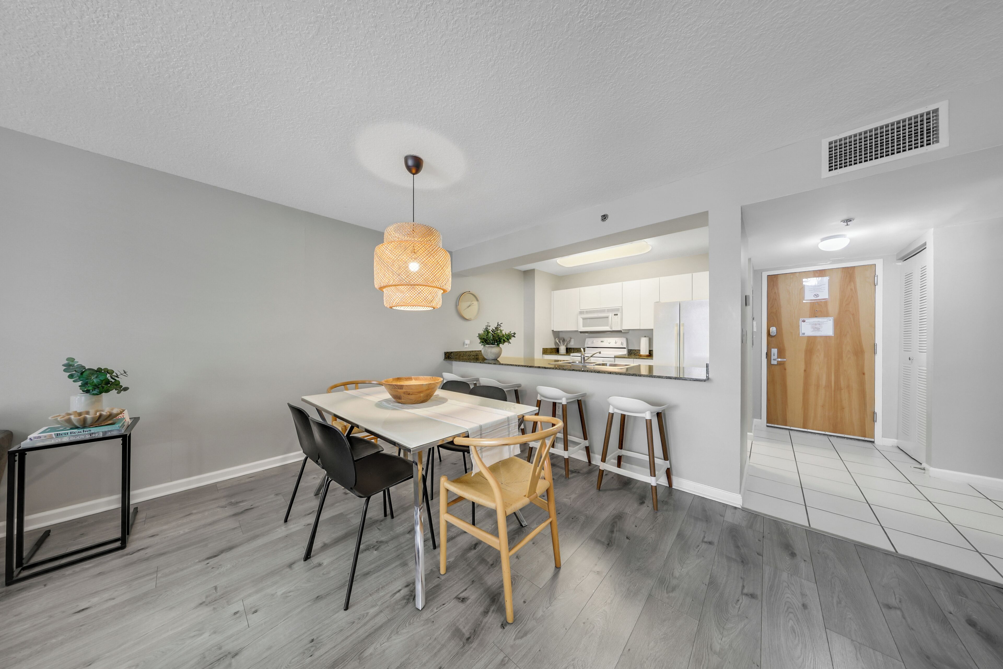 A modern kitchen with white cabinets, a wooden dining table, and black chairs.