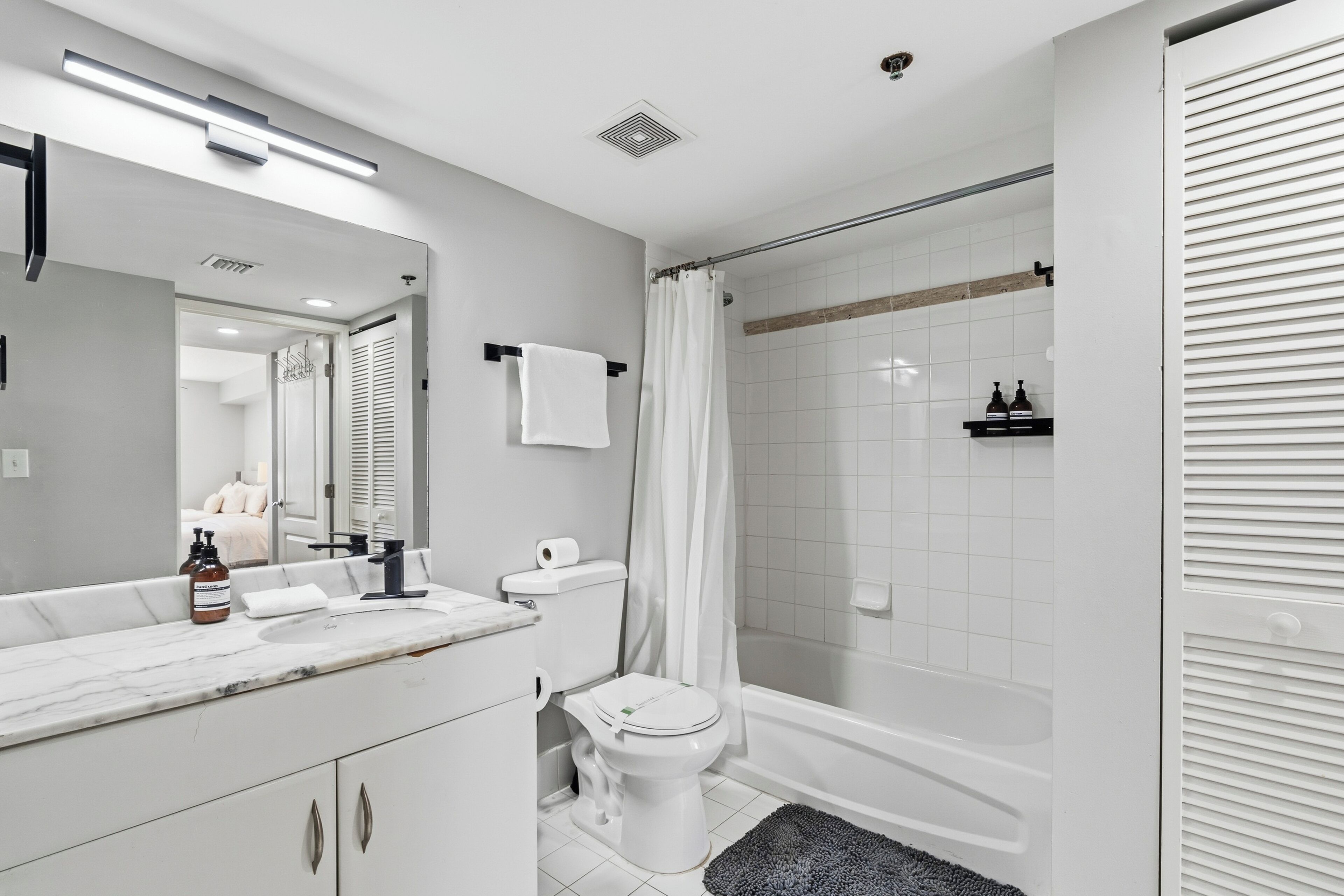Ein modernes Badezimmer mit Waschbecken, Toilette und Badewanne, alles in Weiß.
