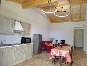 A compact kitchen with a microwave, refrigerator, and wooden ceiling beams.