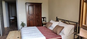 Een slaapkamer met een bed, een kledingkast, een klein tafeltje en een kamerplant.