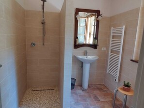Een badkamer met een douche, wastafel en spiegel erboven.