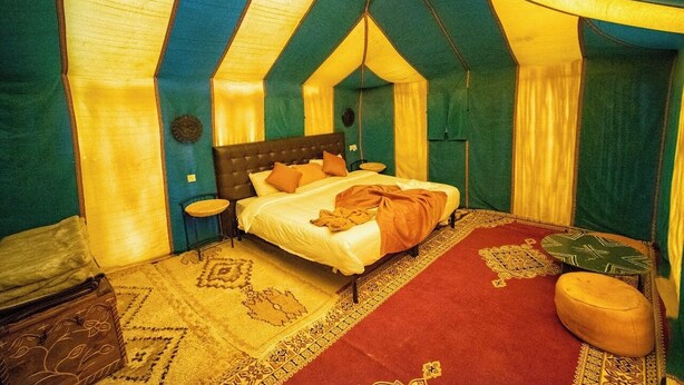 Una habitación acogedora y triangular con cama, una mesita y un banco.