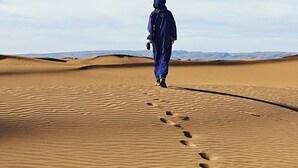 Una persona caminando por un sendero arenoso en un paisaje desértico.