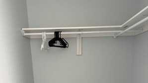 Una stanza con pavimento in legno, pareti grigio chiaro e soffitto bianco con tubature a vista.