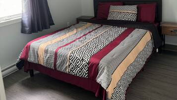 Une chambre à coucher avec un lit, un ventilateur de plafond, une table de chevet et une fenêtre avec des rideaux.