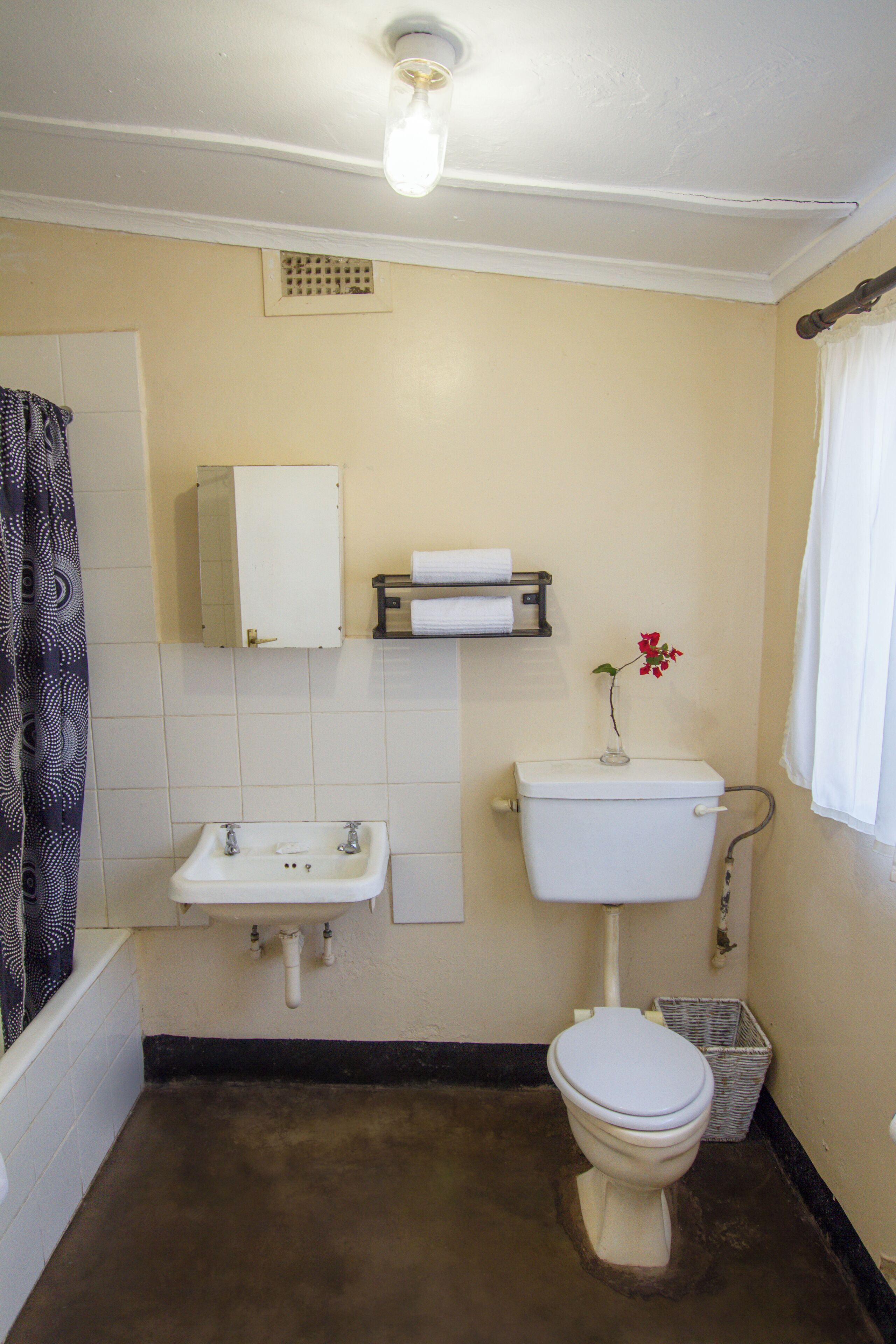 Une salle de bain avec des toilettes, un lavabo et une petite étagère où sont posées des serviettes.