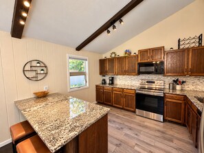 A kitchen with wooden cabinets, a granite countertop, a built-in oven, and a window with a view of greenery. - Scenic getaway in central Flagstaff (Flagstaff)