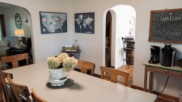 A dining area with a table, chairs, a vase of flowers, a wall with a world map, and a chalkboard with writing.