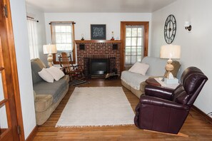 A living room with a fireplace, two sofas, a leather armchair, and a rug.