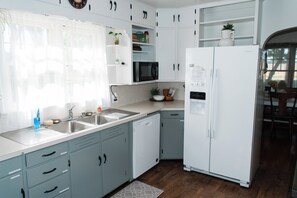 Een moderne keuken met witte kastjes, een roestvrijstalen spoelbak, een magnetron en een koelkast.