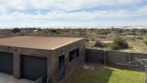 A building with a flat roof, brick walls, and two garage doors. - Sandcastle: 6x2 home with stunning views of both the ocean and the sand dunes  (Lancelin)