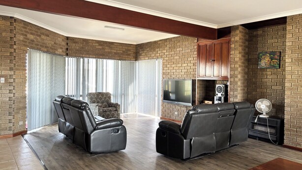 A spacious living room with a brick wall, a flat-screen TV, a sound system, and two reclining chairs. - Sandcastle: 6x2 home with stunning views of both the ocean and the sand dunes  (Lancelin)
