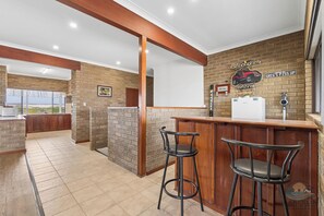 A bar area with a brick wall, a counter, and two stools.