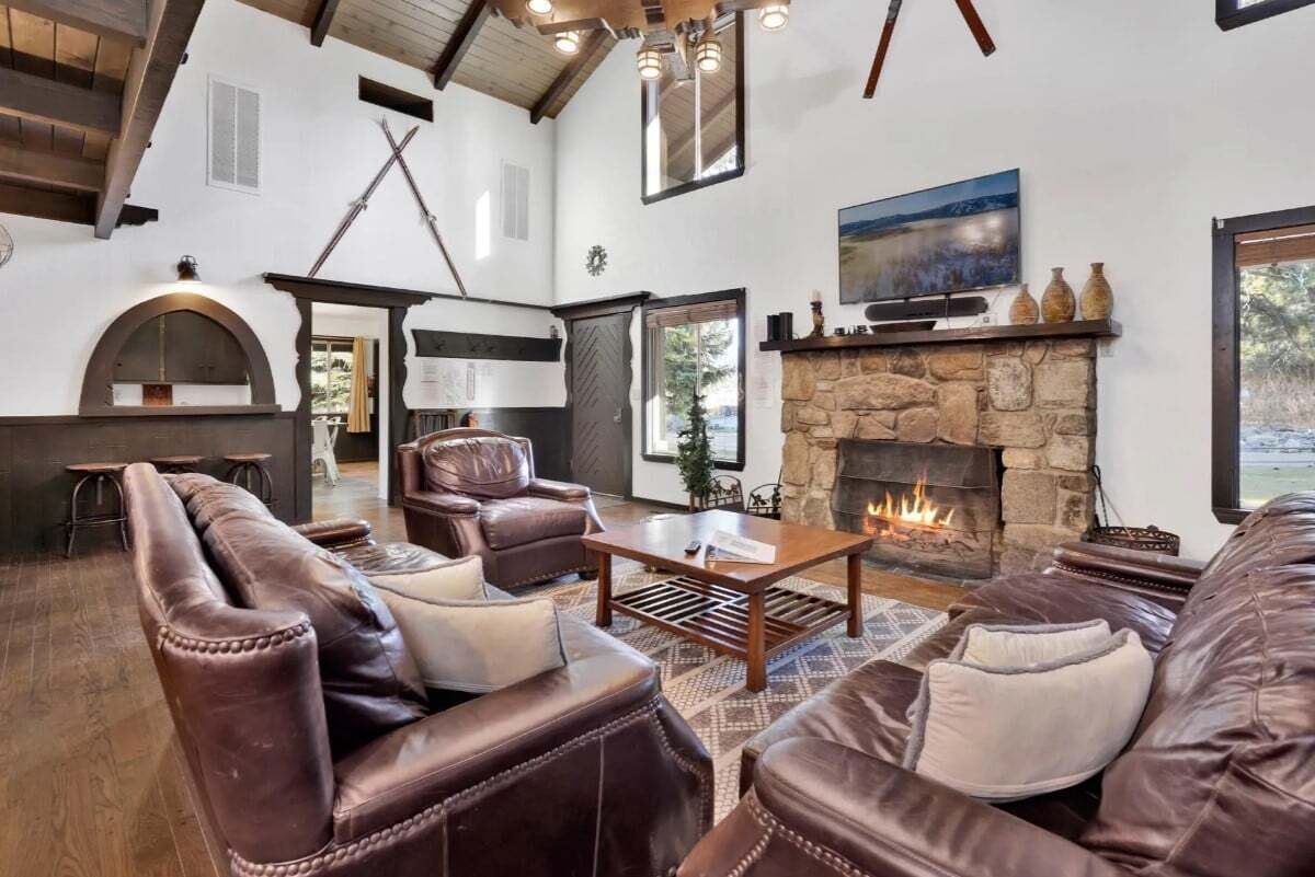 Una sala de estar acogedora con sofás de cuero, chimenea de piedra y televisor.