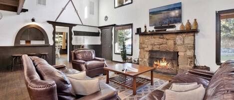 Una sala de estar acogedora con sofás de cuero, chimenea de piedra y televisor.