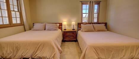 Une chambre avec deux lits, une table de chevet avec des lampes et une fenêtre avec des rideaux.