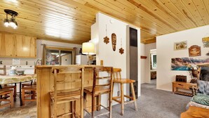 A wooden interior with a kitchen area, dining space, and a living area with a sofa and a table. - Reality Escape #2466 (Big Bear City)