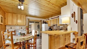 A cozy kitchen with wooden cabinets, a central island, and a dining area with wooden chairs. - Reality Escape #2466 (Big Bear City)